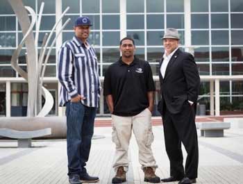 Three men standing in front of a glass building