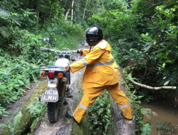 Health worker pushes a motorcycle over a tree bridge