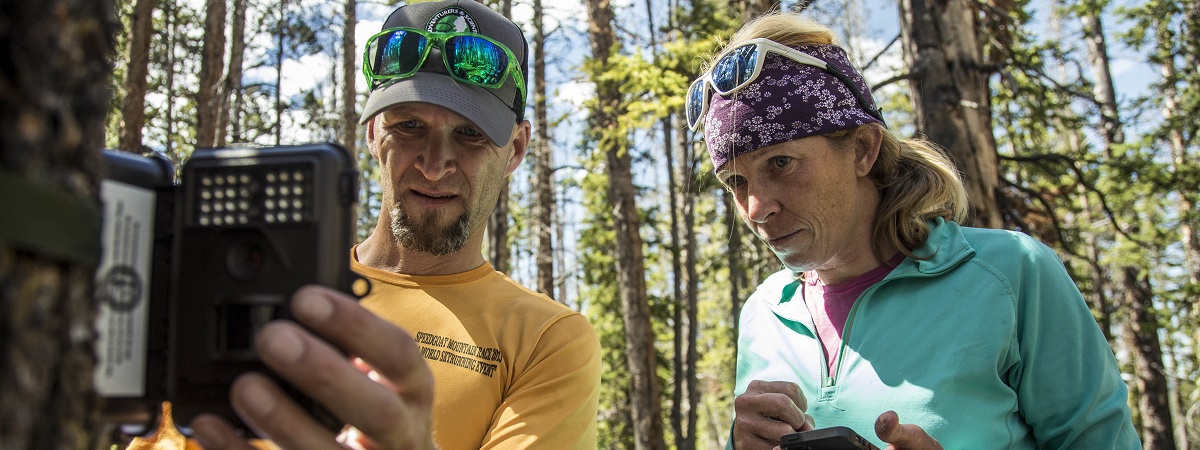 Two adventure scientists check and log data from a checkpoint in the woods