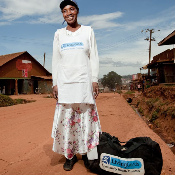 African woman stands smiling on a dirt path