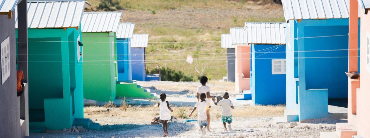 Four children hold hands and skip down a gravel 