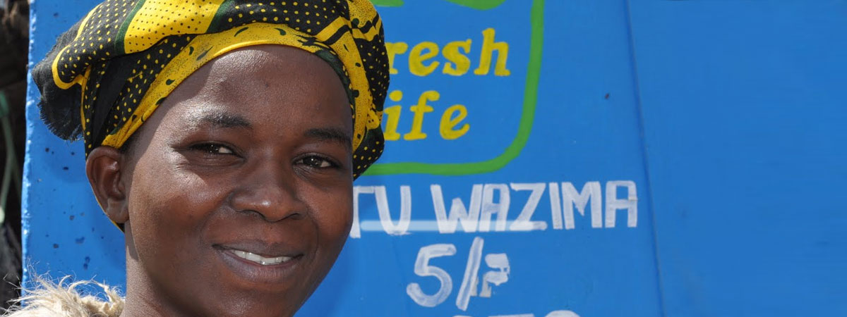 African woman standing next to a fresh life toilet