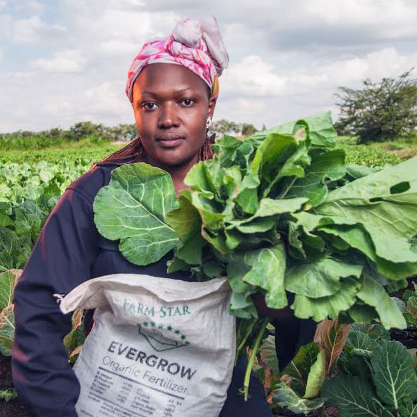 woman with sanergy fertilizer standing in a field