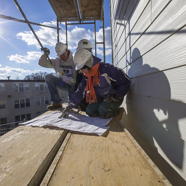 3 volunteers for Habitat for Humanity look at building plans