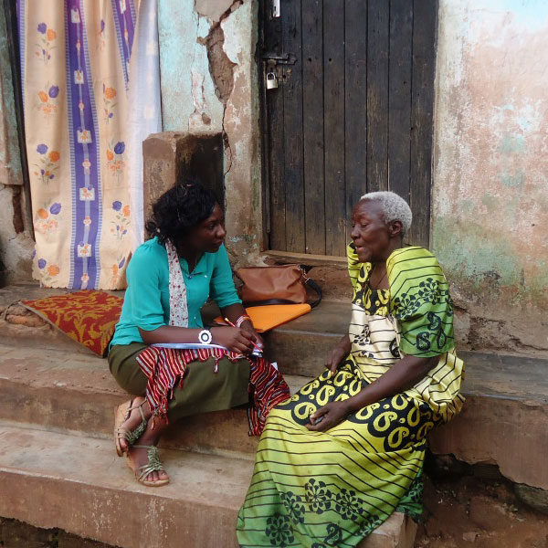 Two African women speaking on the steps of an African home