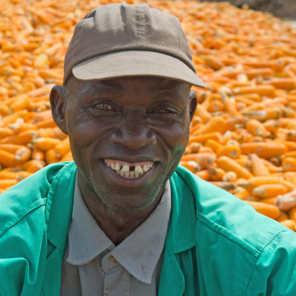 Farmer smiling with his crop in the background