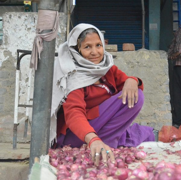 Woman in india crouched down by small red potatoes