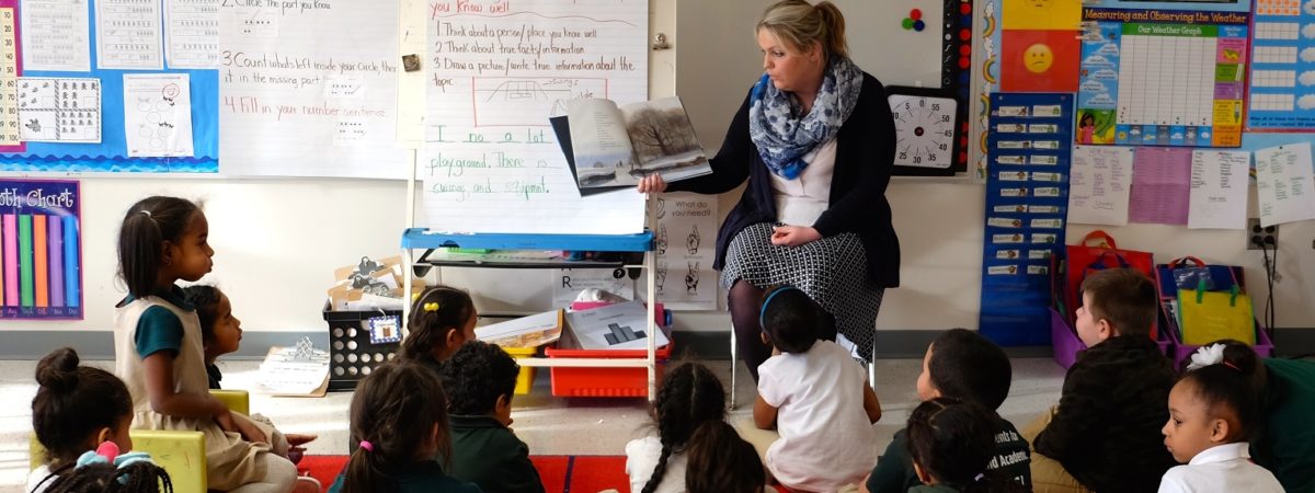 Female teacher reads a book to a classroom full of children