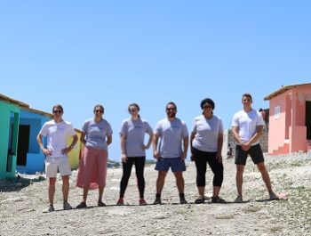 New Story team standing in between a row of homes they built in Haiti