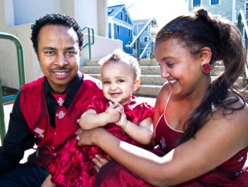 Family sitting on the steps of their home with a daughter in a red dress