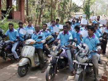 A large group of Indian motorcyclists gather and smile