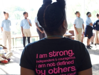 Young black girl stands with her back to the camera wearing an inspiring t-shirt with a message that 