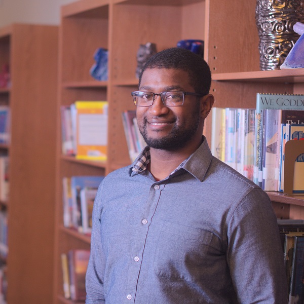 An african american man stands smiling in a library