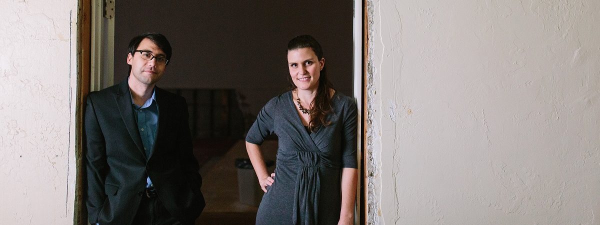 Adrian Tirtanadi and a female member of Open Door Legal stand in an open doorway