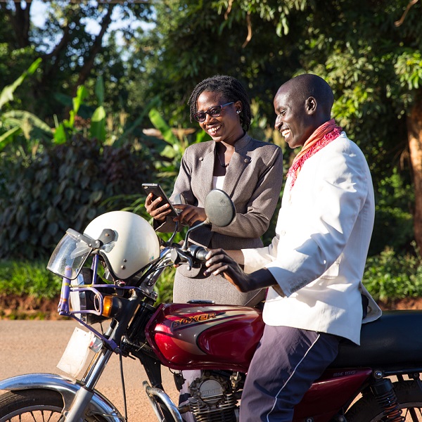 Maureen Nuwamanya demonstrates to boda boda rider Tumwebaze Sam how he can access free legal advice from Barefoot Law through a cell phone.