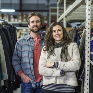 Co-founders of The Renewal Workshop, Jeff Denby and Nicole Basset, stand in the middle of their showroom smiling