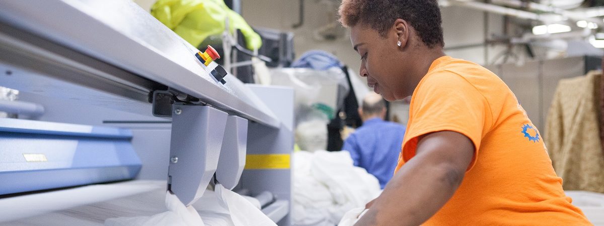 A female Wash Cycle employee folds laundry