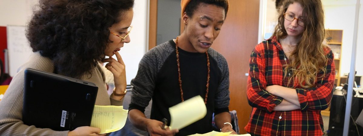 Three Vote.org staff members flip through pages of yellow notes while discussing voter turnout