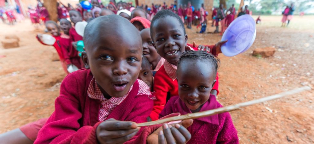 Happy African school children smile and play with utensils