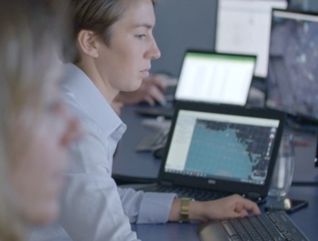 A fmember of the OceanMind team sits in a field office tracking data on multiple computer screens in front of her