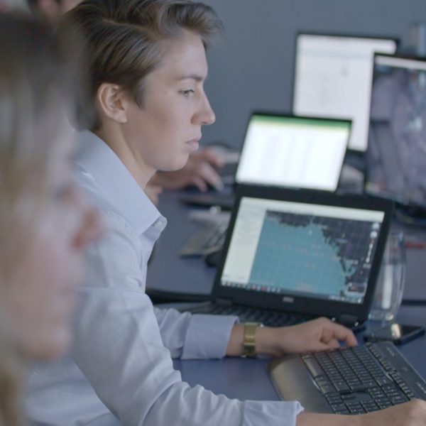 A fmember of the OceanMind team sits in a field office tracking data on multiple computer screens in front of her