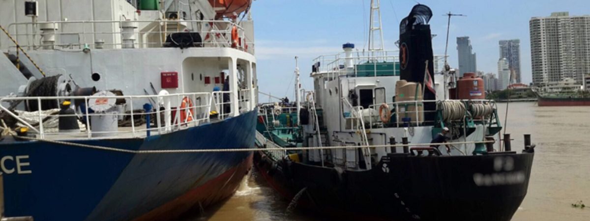 Two large fishing vessels are docked outside a major city