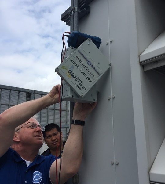 Two men install a WattTime device on an HVAC system