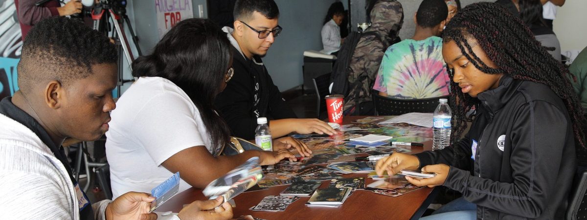 Sutdents gather around a table and sort through images