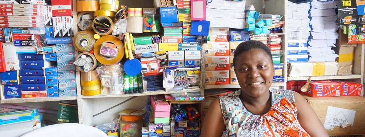 An African female small business owner sits inside of her store front