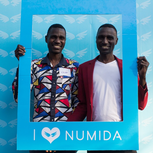 Two African men smile holding a card