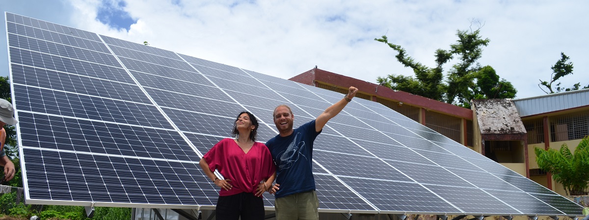 A woman and a man stand in front of solar panels