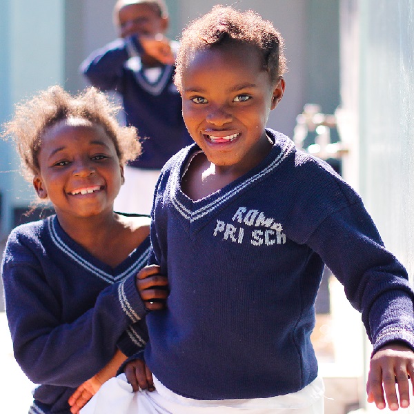 3 African school children smile on the playground