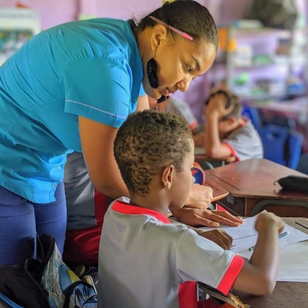 Inside a Costa Rican classroom a teacher leans over the desk of a student to help answer a question