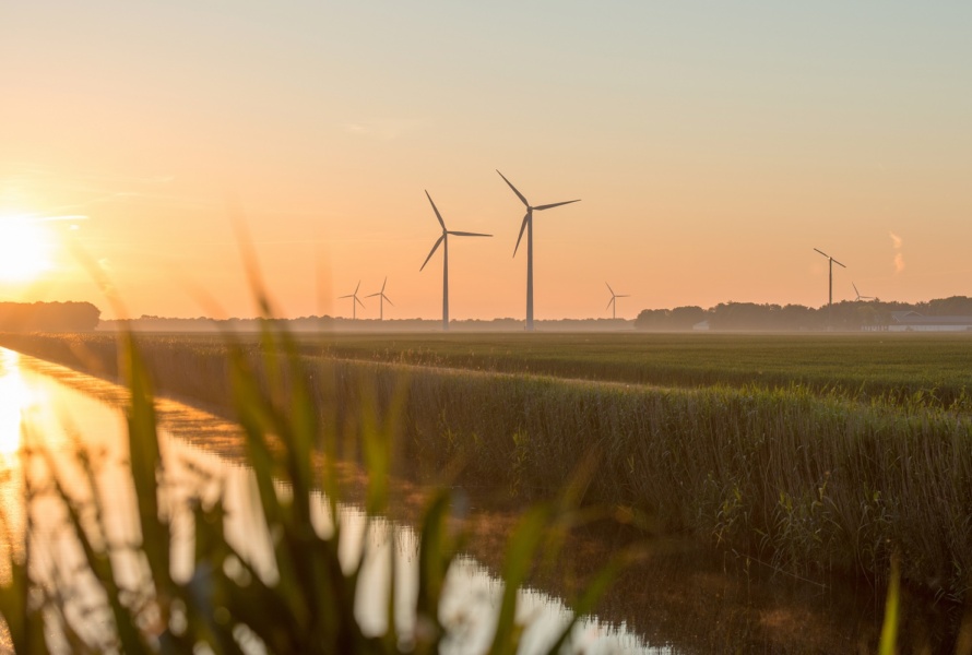 Dawn over a canal with wind turbines in the distance
