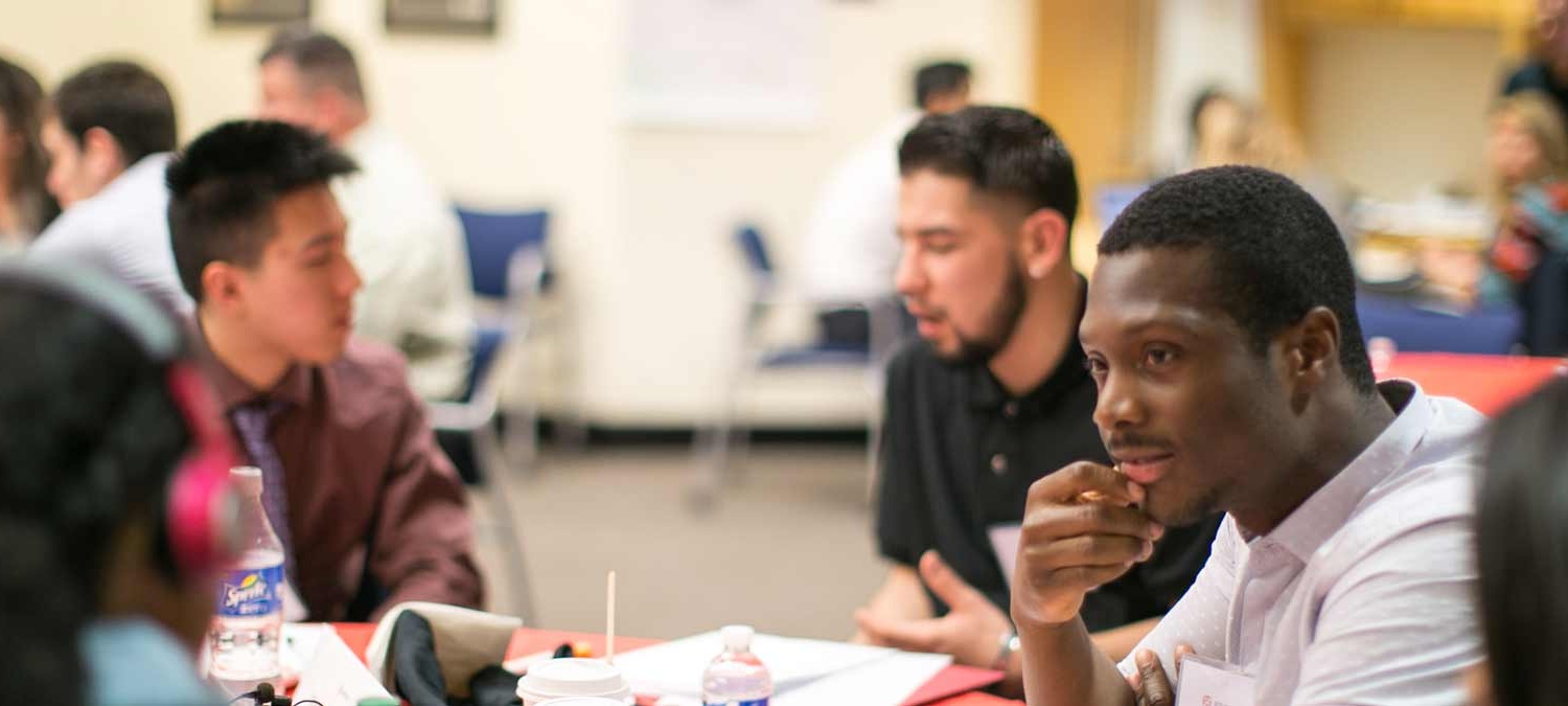 Young man listening attentively in a room full of people