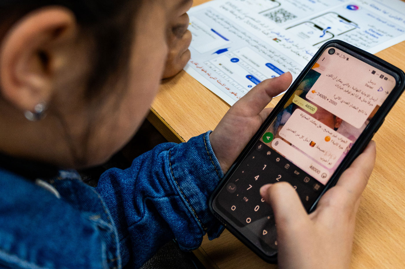 Child typing a number into a chat on a smartphone.