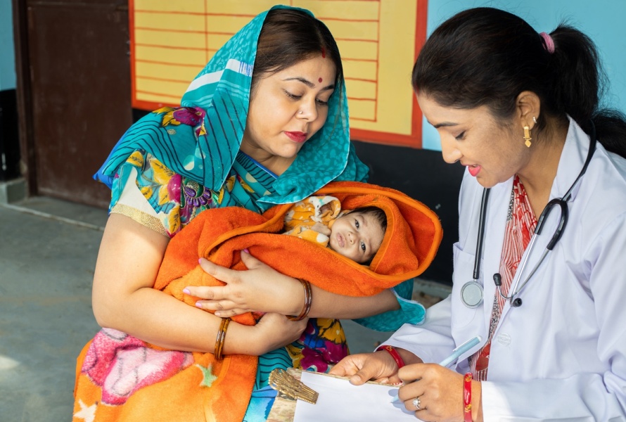Indian pediatrician doctor examine new born baby at village, Mother wearing sari get infant check by medical person. Rural healthcare camp concept.
