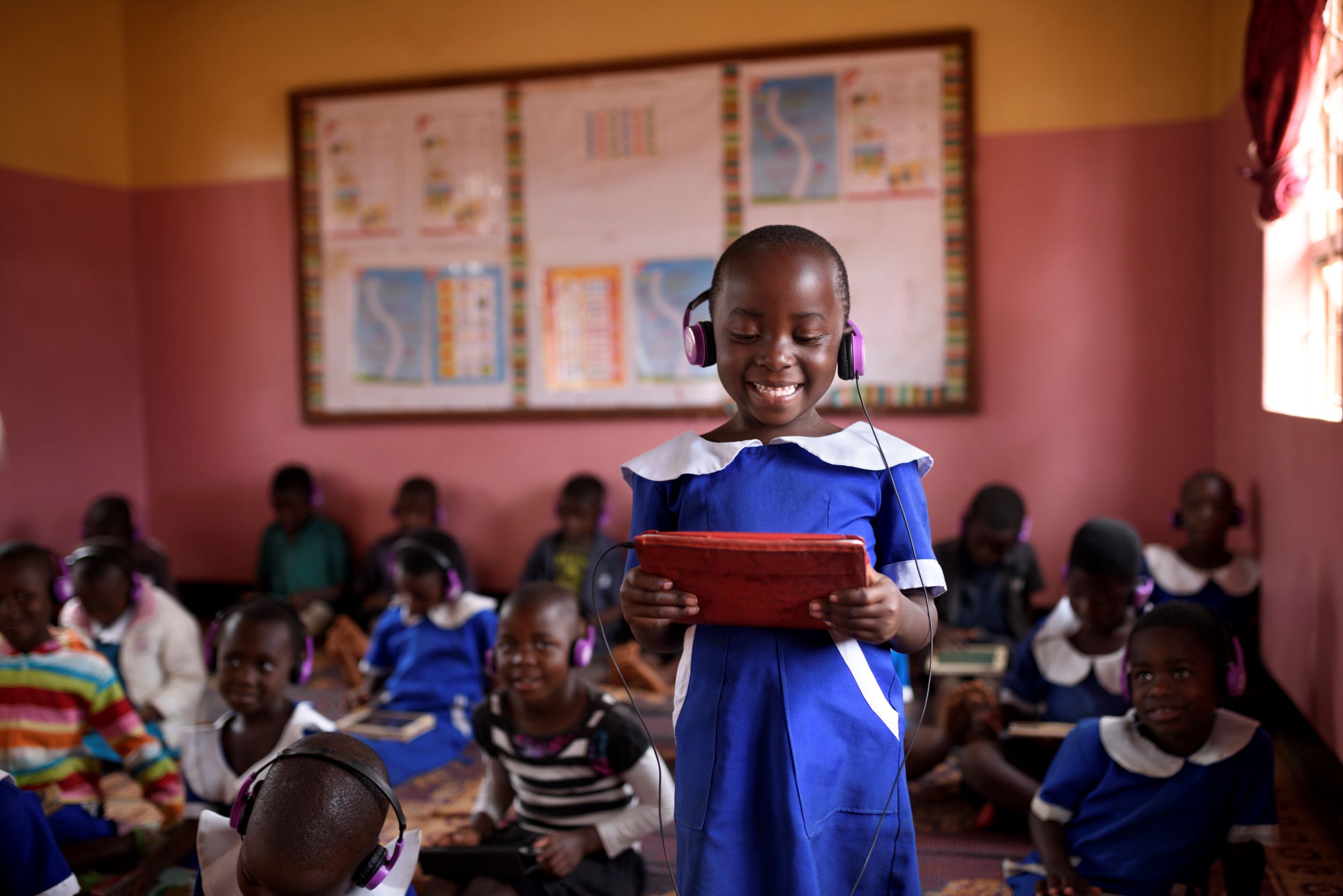 A African student smiles while looking at her learning device