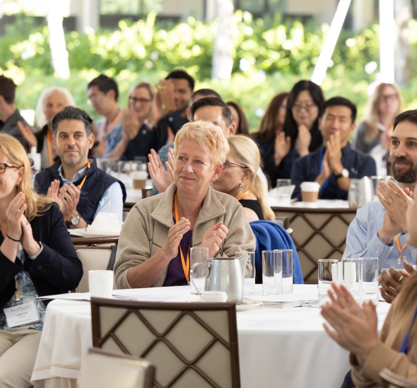 DRK entrepreneurs smile and clap in a large, white tent outdoors