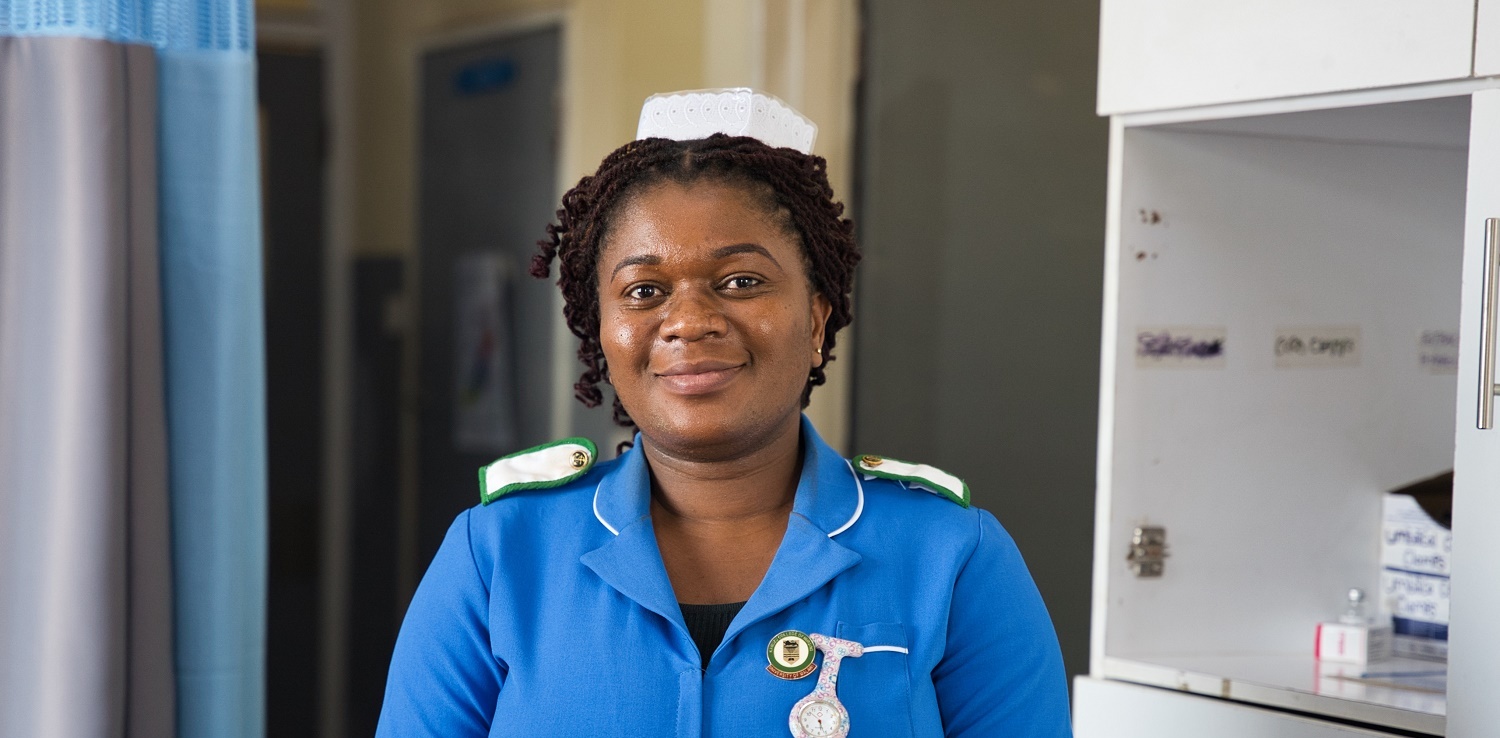 African nurse stands smiling in a hospital room