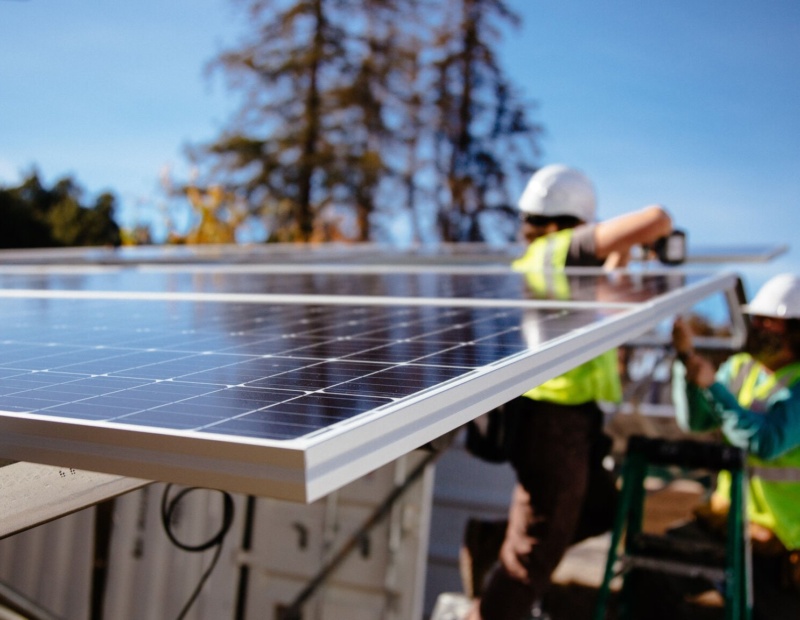 Two people work outside to install solar panels