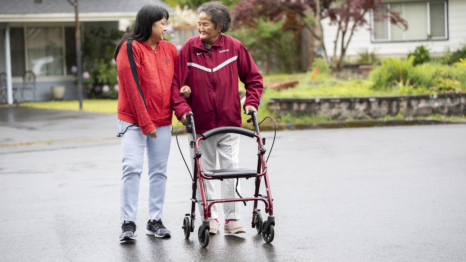 A home health aid supports her patient on a walk outside