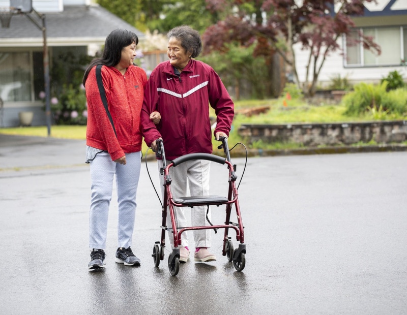 A home health aid supports her patient on a walk outside