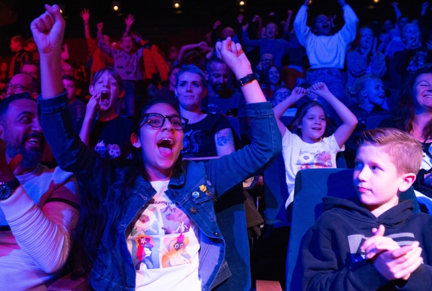 Students engaged in a live learning activity cheer loudly from the stands