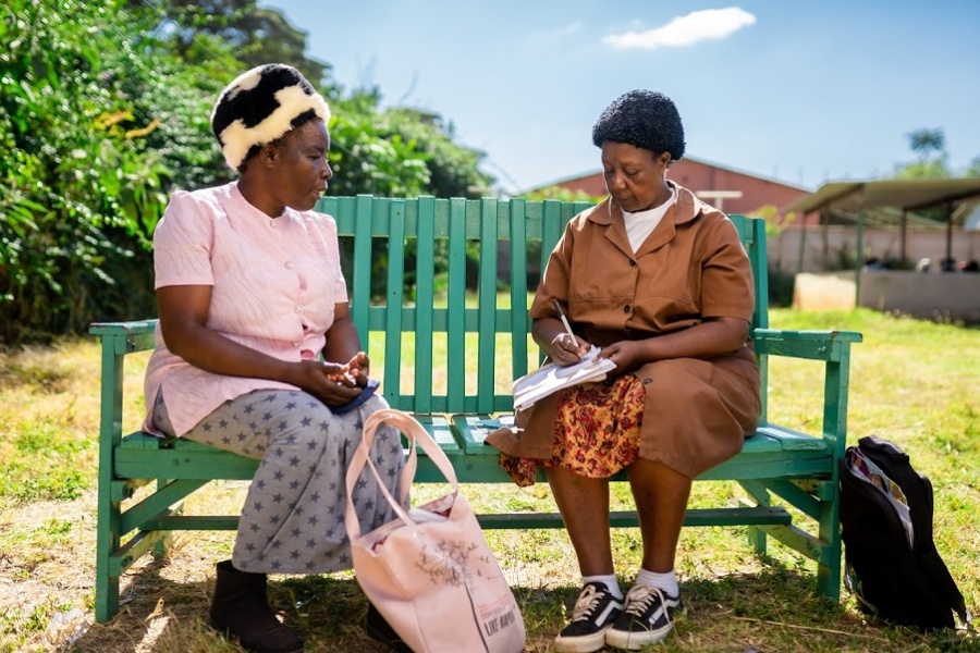 Two African women speak on a Friendship Bench