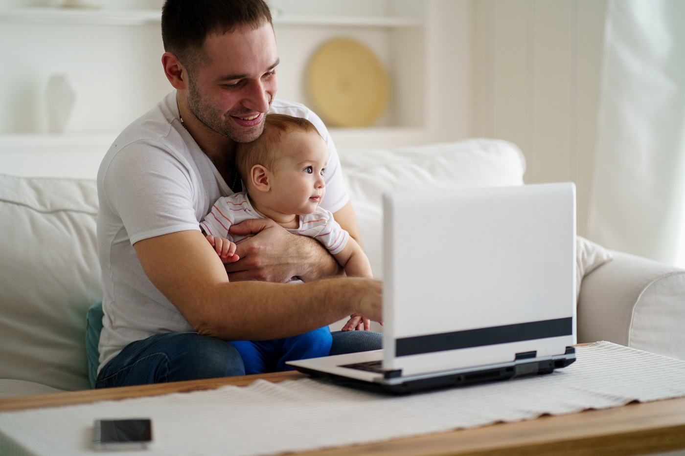 Father multitasking by babysitting and working on computer. dad and son in living room. lifestyle of modern businessman freelancer