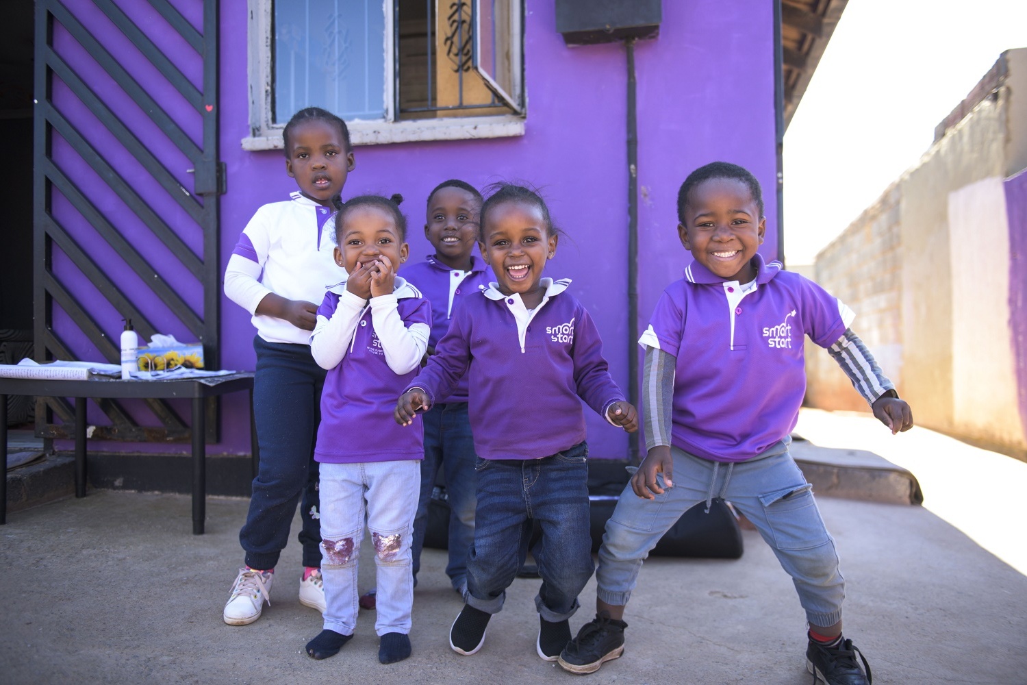 Five smiling African children dressed in purple reading SmartStart.