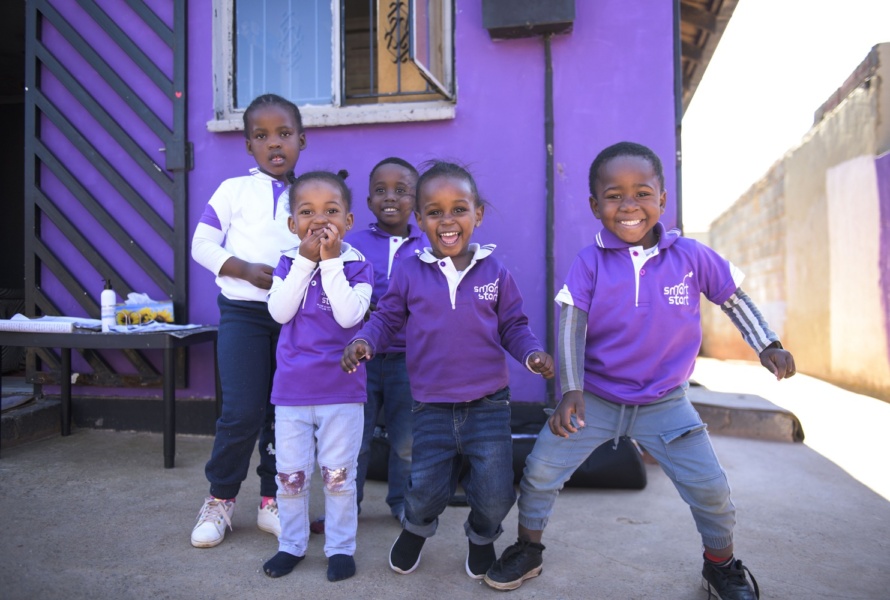 Five smiling African children dressed in purple reading SmartStart.