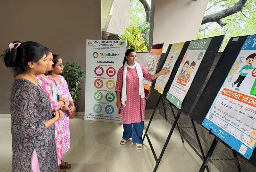 Three Indian woman observed as a fourth woman explains large poster boards with information on them