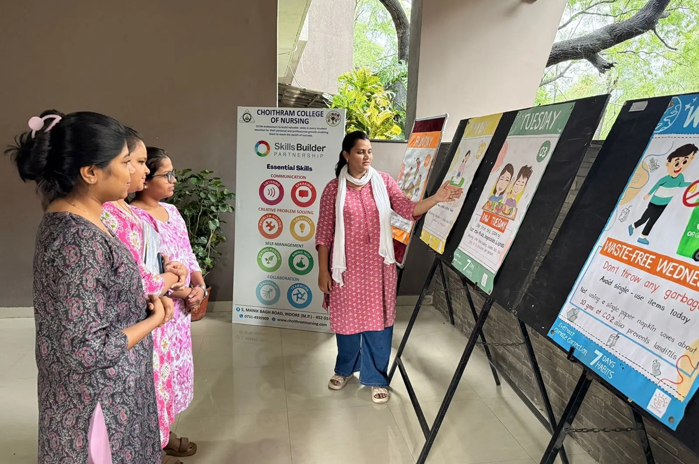 Three Indian woman observed as a fourth woman explains large poster boards with information on them